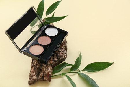 Composition with eyeshadows, tree bark and plant leaves on color backgroundの写真素材