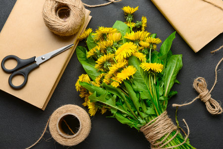 Bouquet of beautiful dandelion flowers, rope, scissors and books on dark background, closeupの写真素材