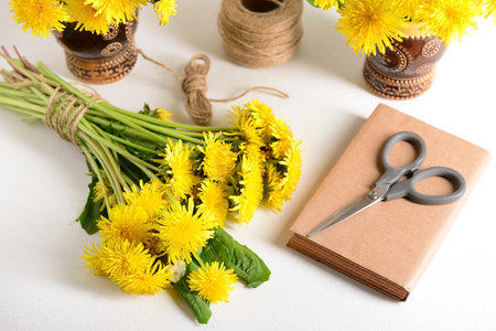 Yellow dandelion flowers, rope, scissors and book on light tableの写真素材