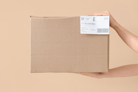Hands of courier with parcel on beige backgroundの写真素材