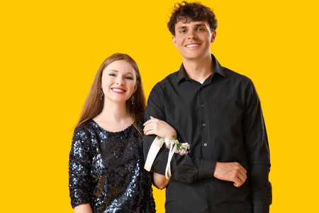 Beautiful prom couple on yellow backgroundの写真素材