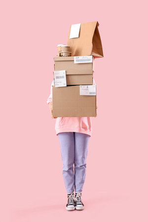 Female courier with parcels and food on pink backgroundの写真素材