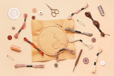 Wooden embroidery hoop with canvas and sewing supplies on pale orange backgroundの写真素材