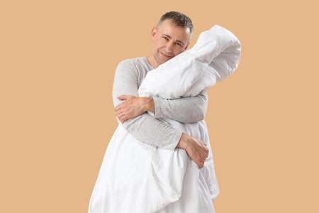 Mature man with soft blanket on beige backgroundの写真素材