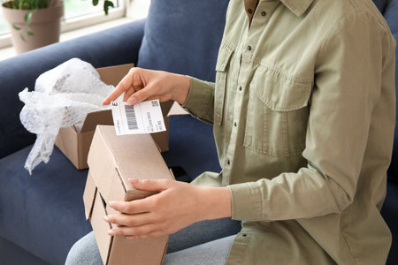 Young woman packing parcel for client at home, closeupの写真素材