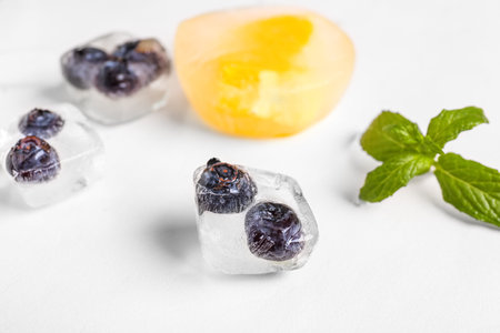 Fresh blueberry frozen in ice cube on light backgroundの写真素材