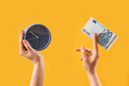 Woman with euro banknote and clock on yellow backgroundの写真素材