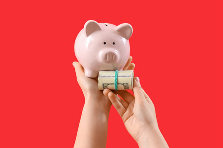 Woman with piggy bank and money on red backgroundの写真素材