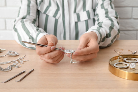Woman cleaning beautiful jewelry at wooden tableの写真素材