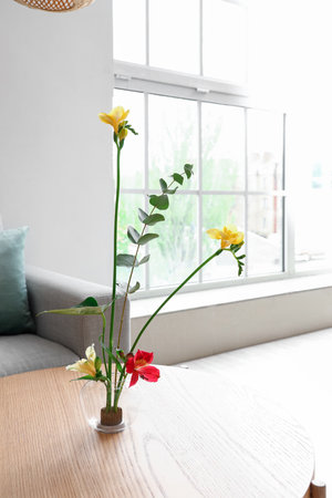 Beautiful ikebana on coffee table in living roomの写真素材
