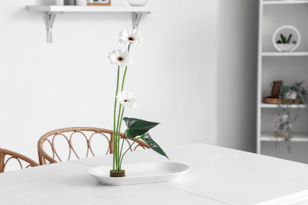 Beautiful ikebana on dining table in roomの写真素材