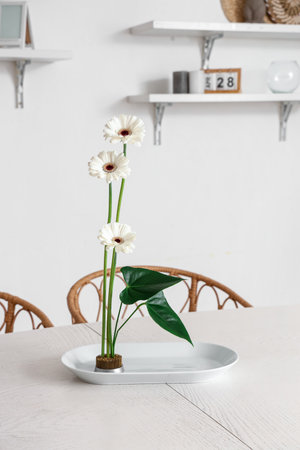 Beautiful ikebana on dining table in roomの写真素材