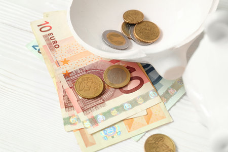 Broken piggy bank with money on white wooden background. concept of failureの写真素材