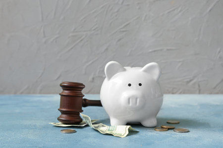 Piggy bank with judge gavel and money on grunge blue background. concept of bankruptcyの写真素材