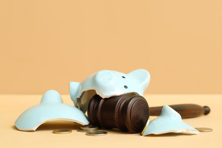 Broken piggy bank with judge gavel and money on orange background. bankruptcy conceptの写真素材
