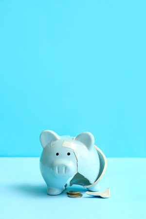 Broken patched piggy bank with money on blue background. bankruptcy conceptの写真素材
