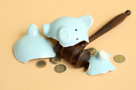 Broken piggy bank with judge gavel and money on orange background. bankruptcy conceptの写真素材