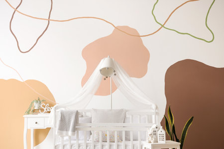 Interior of stylish bedroom with baby crib, lamp and tableの写真素材