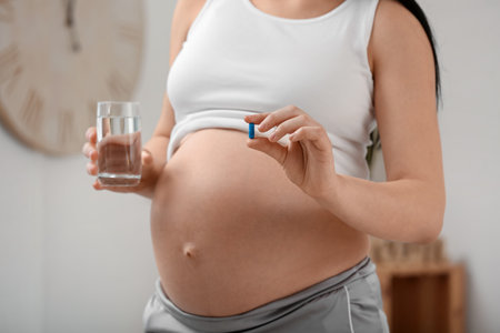 Pregnant woman with Folic Acid pill and glass of water at home, closeupの写真素材