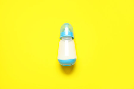 Bottle with milk for baby on yellow background
