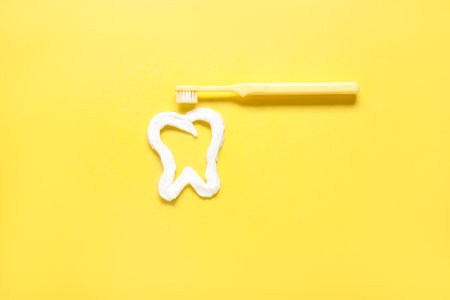 Tooth made of white paste with brush on yellow backgroundの写真素材
