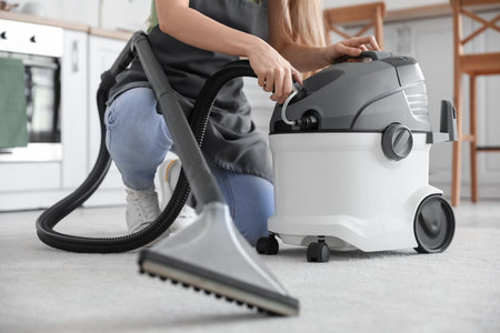 Young woman with vacuum cleaner in kitchen, closeupの写真素材