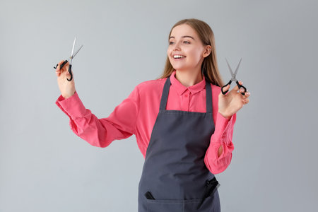 Female hairdresser with scissors on gray backgroundの写真素材
