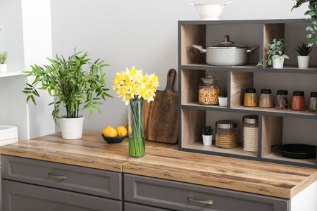 Vase with blooming narcissus flowers on counter in interior of kitchenの写真素材