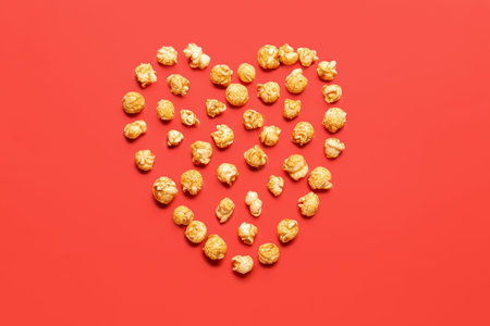 Heart made of crispy popcorn on red backgroundの写真素材