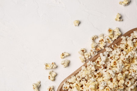 Wooden board with crispy popcorn on light backgroundの写真素材
