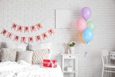 Interior of bedroom decorated for birthday with balloons, gift box and garlandの写真素材