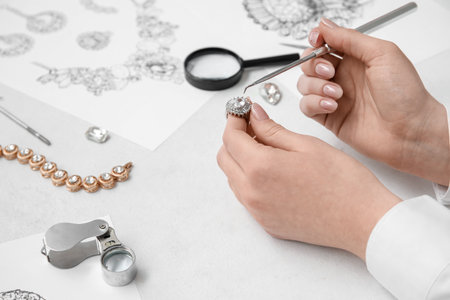 Female jeweler making ring on white table, closeupの写真素材