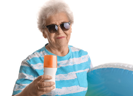 Senior woman with sunscreen cream and inflatable ring on white background, closeupの写真素材