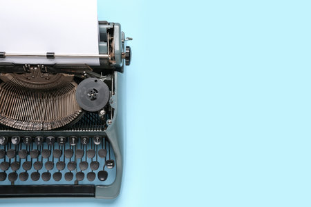 Vintage typewriter with blank paper sheet on blue backgroundの写真素材