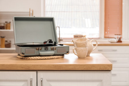 Record player with vinyl disk, cups and teapot on counter in kitchenの写真素材