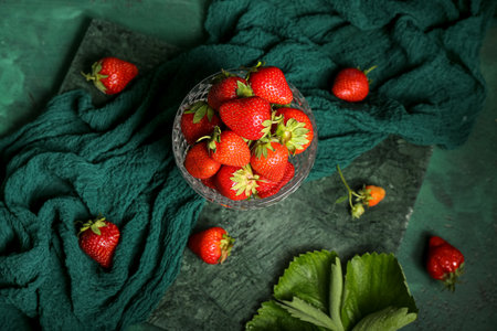 Glass bowl with fresh strawberries on green backgroundの写真素材