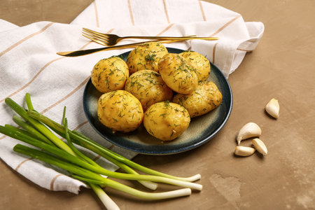 Plate of boiled baby potatoes with dill and green onion on brown backgroundの写真素材