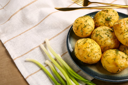 Plate of boiled baby potatoes with dill and green onion on brown backgroundの写真素材
