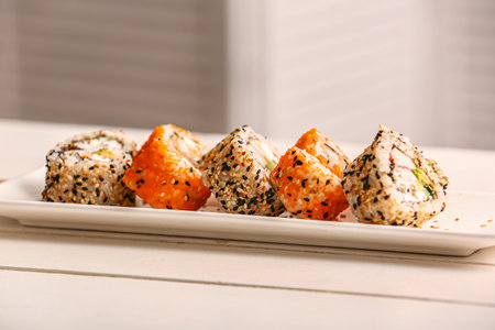 Plate with tasty sushi rolls on white wooden tableの写真素材
