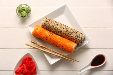 Plate with tasty sushi rolls, ginger, wasabi and soy sauce on white wooden backgroundの写真素材