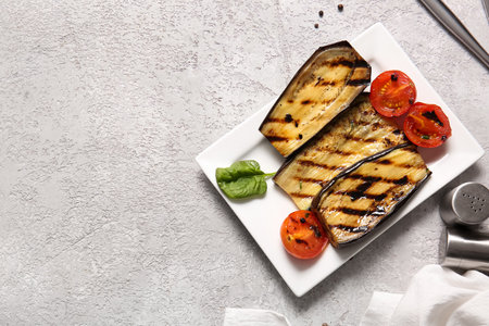 Plate with delicious grilled eggplants and tomatoes on gray backgroundの写真素材