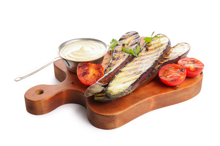 Board with delicious grilled eggplants, sauce and tomatoes on white backgroundの写真素材