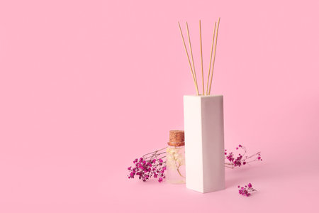 Floral reed diffuser and gypsophila flowers on pink background