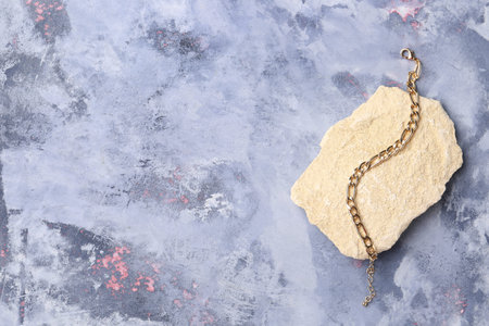 Stone with beautiful chain bracelet on blue background
