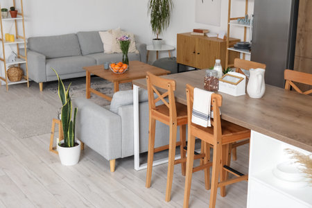 Interior of light open plan kitchen with island table and gray sofas