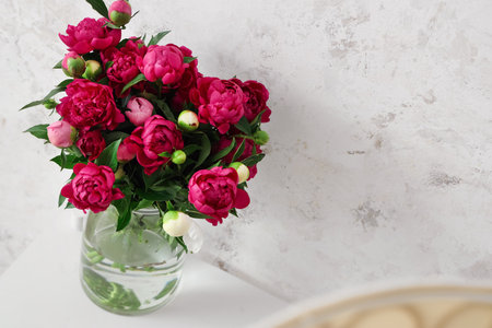 Vase with red peonies near beige grunge wallの写真素材
