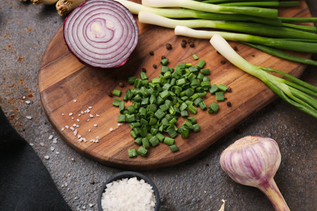 Board with slices of fresh scallion and onion on dark backgroundの写真素材