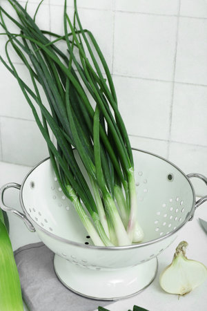 Colander with green onion on light background, closeupの写真素材