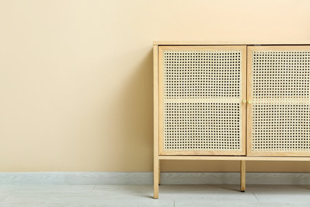 Wooden chest of drawers near beige wall in roomの写真素材