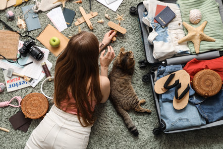 Woman with Scottish fold cat and traveling accessories on green carpet, top viewの写真素材
